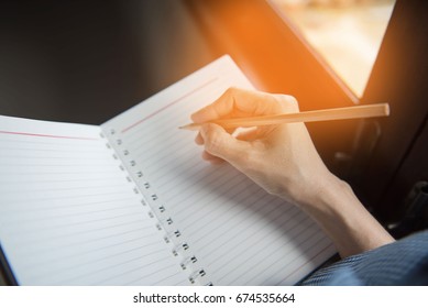 Closeup hand Woman writing notebook with pencil .