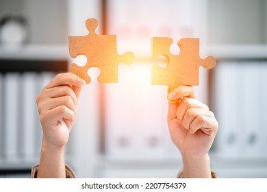 Closeup Hand Of Women Connecting Pieces Of A Jigsaw Puzzle With Orange Light, Business Connection, Success, Solution, And Strategy Concept.