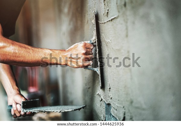 closeup hand of worker plastering\
cement at wall for building house                               \
