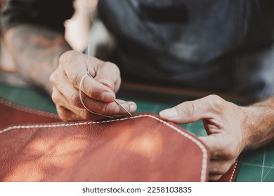 closeup hand working process leather handcraft in the leather workshop. Man holding crafting tool and working. He is sewing hammer to make a walet. Tanner in old tannery. - Powered by Shutterstock