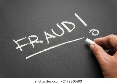 Closeup hand write a FRAUD topic with chalk on the chalkboard