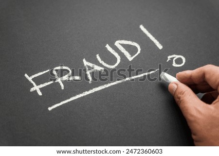 Closeup hand write a FRAUD topic with chalk on the chalkboard