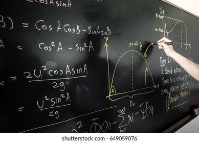 Closeup Of Hand Writing Complicated Math Equation On Black Board. Vintage Background