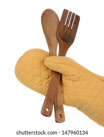 Closeup Of A Hand In A Yellow Oven Mitt Holding A Wooden Spoon And Fork, Isolated On White.