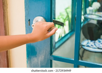 Closeup Hand Of A Young Girl At The Door Knob, Going To Open A Wooden And Glass Door To Go Inside The Cafe