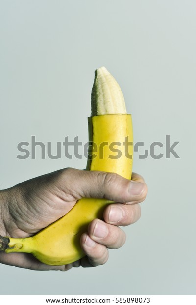 closeup of\
the hand of a young man with a banana with the tip of its skin\
removed, depicting a circumcised male\
member