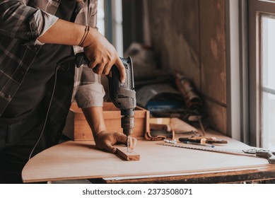 close-up hand a Young man Carpenter works on woodworking machinery in a carpentry shop. The workshop looks professional, highly skilled, and the craftsmen are true craftsmen. - Powered by Shutterstock