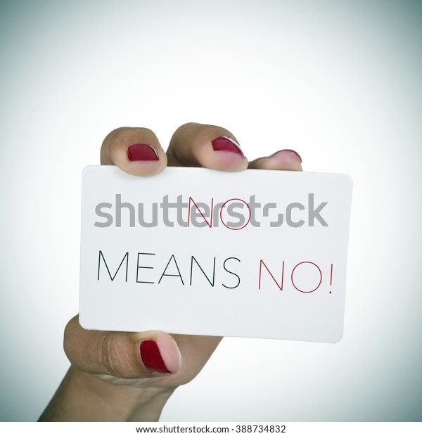 closeup of the hand of a young woman with red polished nails holding a signboard with the text no means no