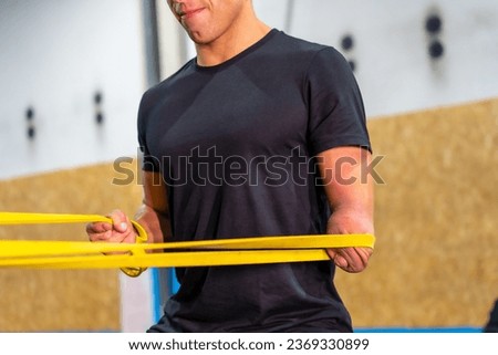 Close-up of a handicapped man using an elastic band to work out in a cross training gym
