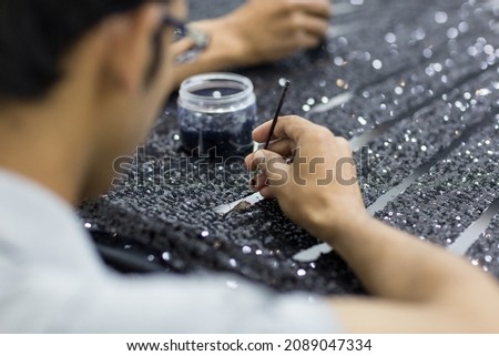 Closeup of handicraft tailor embroidering black sequins beads onto tulle. Making a high fashion dress.