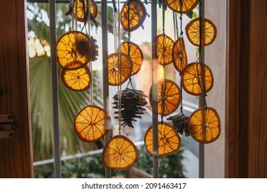 Close-up of handmade garland out of dried orange slices, pinecones on a glass door shot in counter daylight - Powered by Shutterstock