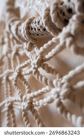 Close-up of a handmade macrame wall hanging. The intricate knots and patterns are visible, showcasing the craftsmanship and texture of the natural fibers.