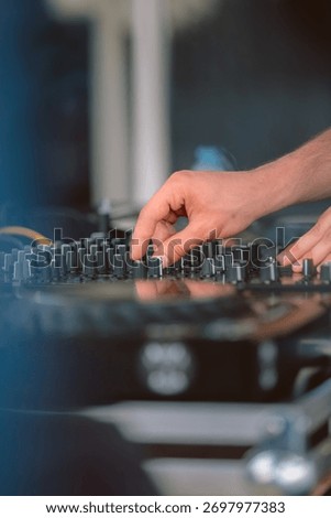 Close-up of DJ’s hands adjusting volume and equalizer on a mixer during a dance party, representing nightlife and entertainment.