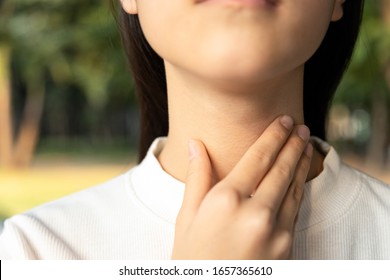 Closeup Of Hands Of Asian Female People Holding Her Inflamed Throat Or Tonsillitis,child Girl Touch The Neck With Her Hands,woman Has Fever,sore Throat Pain Irritation,hard To Swallow Or Loss Of Voice