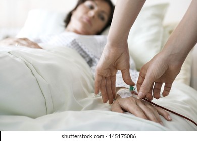 Closeup of hands attaching intravenous tube to patient's hand in hospital bed - Powered by Shutterstock