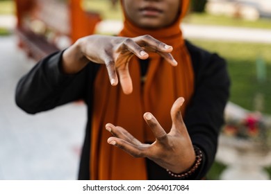 Close-up hands of black muslim woman at qigong chinese meditation and sport training outdoor. African girl is meditating outdoor near chinese arbor