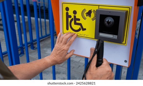 Close-up of the hands of a blind elderly woman reading a text in braille. Button for calling help for people with disabilities.  - Powered by Shutterstock