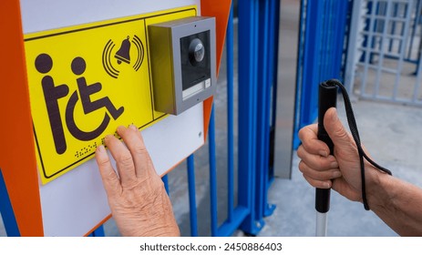 Close-up of the hands of a blind elderly woman reading a text in braille. Button for calling help for people with disabilities.  - Powered by Shutterstock