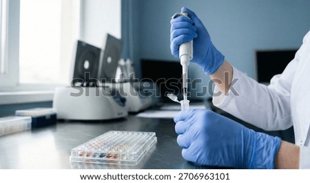 Close-up of hands in blue gloves using an eyedropper to dispense a liquid onto an empty plate on the table.