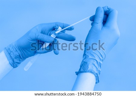 Close-up of hands in blue protective gloves holding a test tube of coronavirus swab collection kit for taking OP NP patient sample sample, PCR DNA testing protocol process. PCR test. Toned