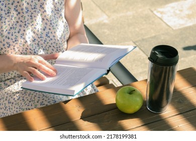 Close-up Of Hands With An Book. Woman Reads A Book Near The Office During A Work Break. Lunch Break On A Summer Day.