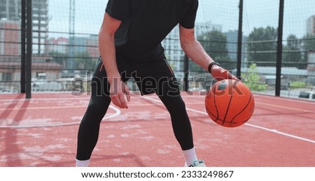 Closeup hands bouncing basketball ball. Man is practicing exersice hitting basketball ball training on court in city. Workout. Sport activities.