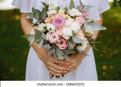 
Close-up of the hands of a bride who is holding a wedding bouquet of flowers. Wedding day.