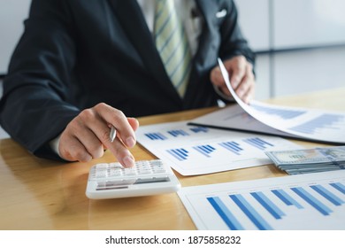 Closeup hands of a businessman working on desk office with using a calculator to calculate the numbers and examine the investment report, finance accounting concept