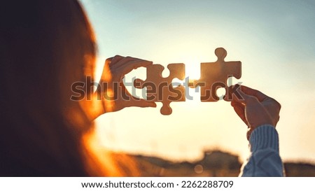 Closeup hands of businesswoman connecting jigsaw puzzle with sunlight effect, Jigsaw alone wooden puzzle against sunset, Business partner, Success and strategy concept