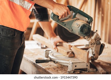closeup hand's carpenter using electric circular saw for cutting wooden boards, on a piece of wood in workshop(vintage tone)