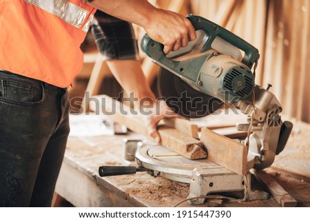 closeup hand's carpenter using electric circular saw for cutting wooden boards, on a piece of wood in workshop(vintage tone)