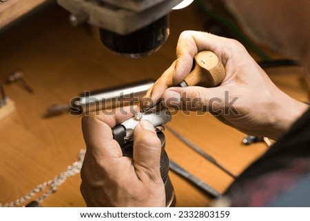 Close-up of the hands of a Caucasian jeweler who fixes a precious stone in a gold ring. Jewelry, manufacturing.