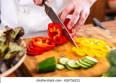 Closeup of hands of chef cook cutting vegetables on wooden table  - Powered by Shutterstock