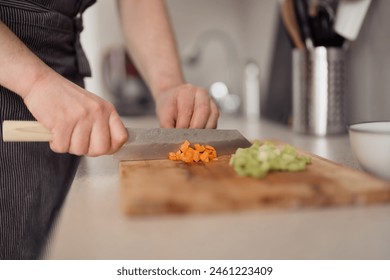 Close-up of hands chopping fresh vegetables on a wooden cutting board in a home kitchen. - Powered by Shutterstock