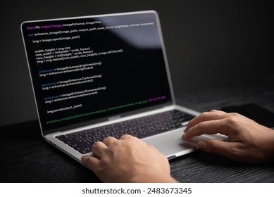 Close-up of hands coding on laptop, displaying programming interface. Represents software development, technology. Suitable for IT, educational content.