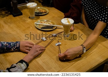 Closeup of hands with coffee cups in a cafe. Hen party in the background. Cheerful girls evening