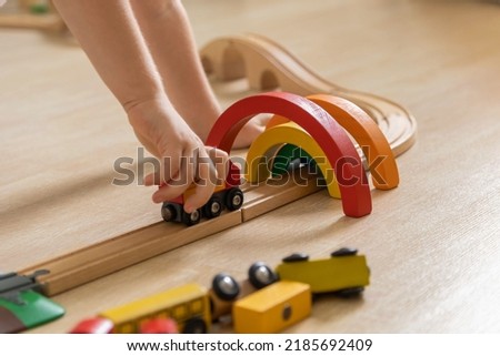 Closeup hands cute baby boy playing wooden rainbow arch and railways eco friendly Montessori materials. Male kid with early educational cars trucks trains natural toys enjoy happy childhood