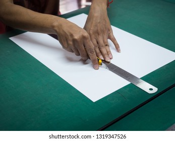 Close-up hands cutting white paper with cutter and iron ruler on green mat - Powered by Shutterstock