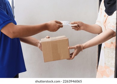 Close-up hands of delivery man receive paying cash payment package courier parcel from customer while giving package.   - Shutterstock ID 2263946065