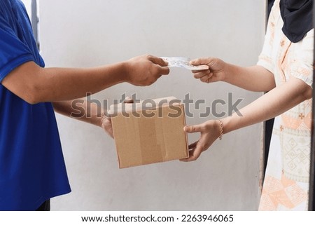 Close-up hands of delivery man receive paying cash payment package courier parcel from customer while giving package.  