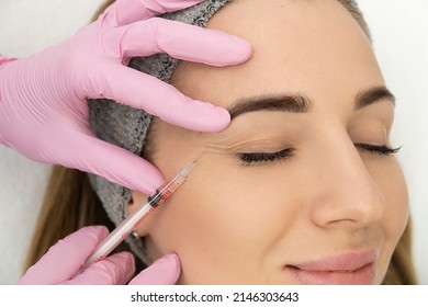 Close-up Of The Hands Of An Expert Cosmetologist Injecting Botox Into A Woman's Forehead. Correction Of Forehead And Eye Wrinkles With Botulinum Toxin.