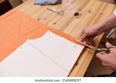 Close-up. Hands of a fashion designer, dressmaker, tailor, cutting fabric near sewing pattern. Woman cutting out a pattern paper in silk fabric. Fashion atelier, tailoring, handmade clothes concept. - Shutterstock ID 2160898297
