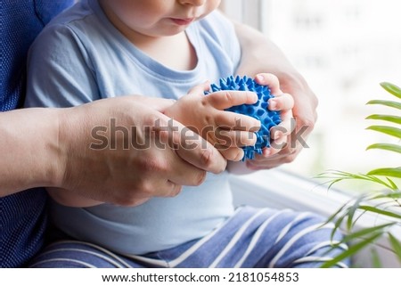 Closeup hands of father and baby boy toddler with prickly massage ball. Sensory or tactile activities. Children health. Massage textured balls for kids. Earlier development. Focus picked.