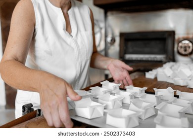 Close-up of the hands of a female baker preparing tray with small containers for bakery products - Powered by Shutterstock