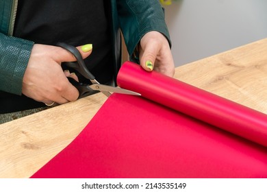 Close-up Of The Hands Of A Female Florist Cutting With Scissors Colored Bright Pink Wrapping Paper For A Bouquet In A Flower Shop