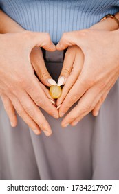 Close-up Of Hands In The Form Of A Heart Of A Young Married Couple, Holding Grapes As An Egg, An Embryo. Pregnancy Early Term, Expectation Of A Baby.