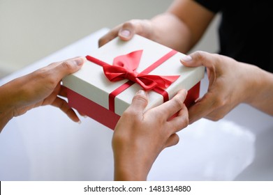 Closeup Of Hands Giving Gift Box In Christmas Day And New Year Festival To Each Other. Holiday And Event. Surprising Giftbox In Dating On End Year Party. People Lifestyle And Object Concept.