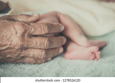 Closeup Hands Of Grandmother Holding The Foot Of The First Grandchild
