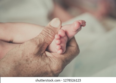 Closeup Hands Of Grandmother Holding The Foot Of The First Grandchild
