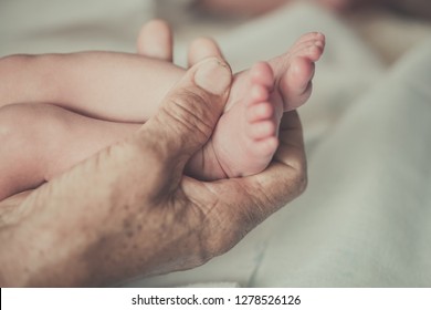 Closeup Hands Of Grandmother Holding The Foot Of The First Grandchild
